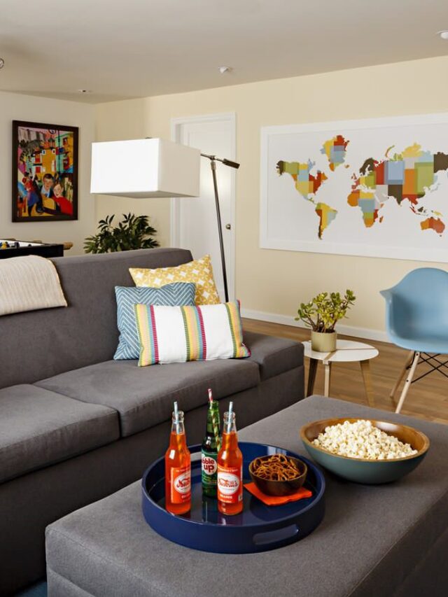 Cropped - Chic Basement Charcoal Sofas, Colorful Pillows, Cream Walls and Some Snacks Over The Table